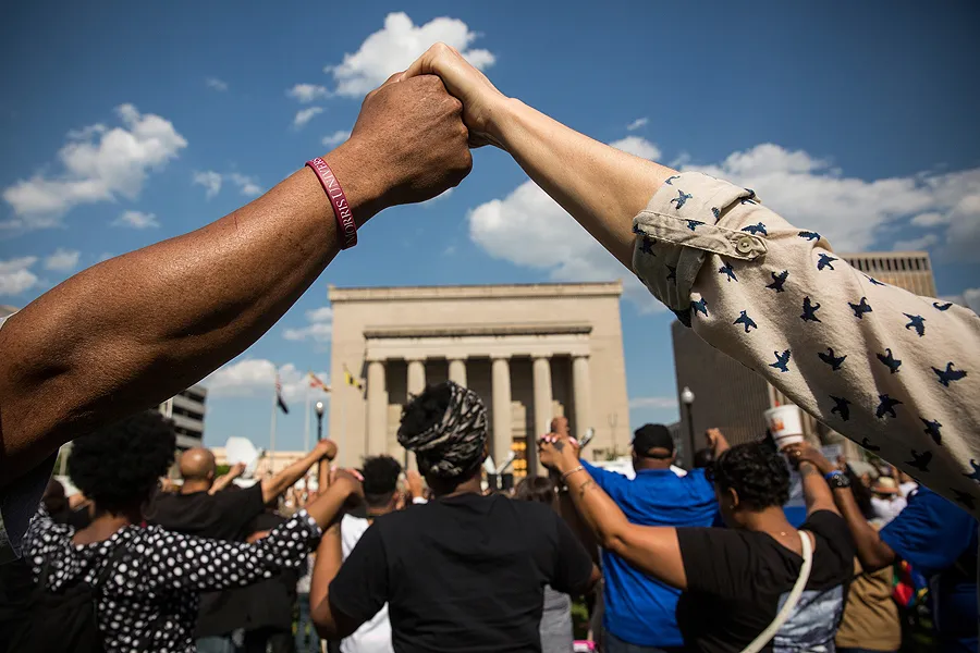 People hold hands during a rally lead by faith leaders in front of Baltimore City Hall on May 3, 2015 in Baltimore, Maryland. Credit: Andrew Burton/Getty Images.