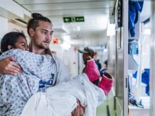 Erik Dike, a rising senior nursing student at Belmont Abbey College, carries a patient onboard a hospital ship in Madagascar during a two-week program with Mercy Ships.