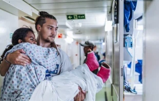 Erik Dike, a rising senior nursing student at Belmont Abbey College, carries a patient onboard a hospital ship in Madagascar during a two-week program with Mercy Ships. Credit: Joshua Kiew Wing Chau