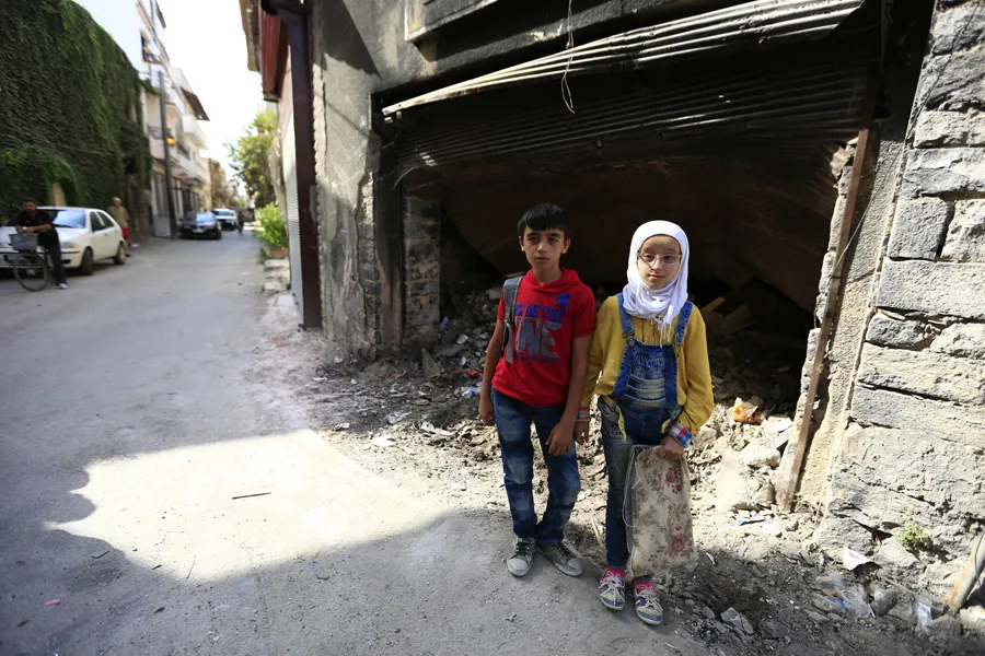 12-year-old twins stand near garbage outside a building in the old city of Homs, Syria. ?w=200&h=150