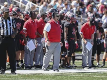Mike Gutelius (center), head football coach of The Catholic University of America, watches the action on the sidelines.