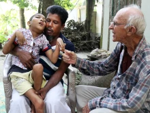 Abdul Mannan Khan and his disabled son Abu Mosa Khan meet with Father Robert Terence McCahill at their home in Munshigonj district, Bangladesh, on Nov. 18, 2025. The priest visits villages daily to find disabled children and connect them with medical treatment.