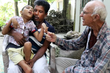 Abdul Mannan Khan and his disabled son Abu Mosa Khan meet with Father Robert Terence McCahill at their home in Munshigonj district, Bangladesh, on Nov. 18, 2025