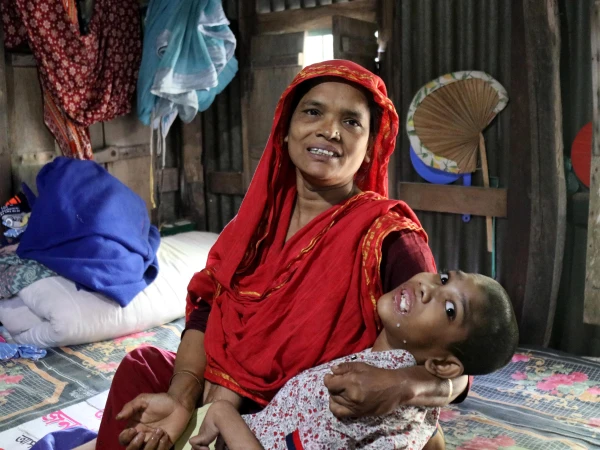 Abu Mosa Khan in his mother's arms at their home in Munshigonj district, Bangladesh, on Nov. 18, 2025. Through Father Robert McCahill's help, the family has access to free hospital treatment in Dhaka. Credit: Stephan Uttom Rozario
