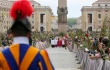Swiss Guards and faithful pilgrims holding olive branches line the processional route in St. Peter’s Square for Palm Sunday celebrations, April 13, 2025. The ancient Vatican obelisk stands at the center of the square as clergy process toward the basilica.