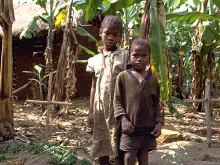 AIDS orphans Dominic, 7, and her sister Reticia, 10, standing between parent's graves in this December 2000 file photo. 