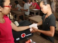 A 12-year-old girl practices bandaging a hand during a first-aid training clinic in Laos. 