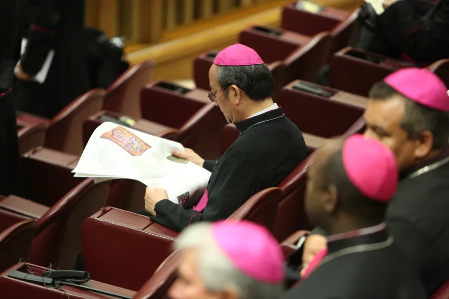 A bishop reads a newspaper in the Vatican's Synod Hall. ?w=200&h=150