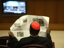 A cardinal peruses the news in the Vatican's Synod Hall during the Extraordinary Synod on the Family, Oct. 10, 2014. 