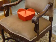 A cardinal's biretta rests on an empty chair. 
