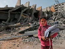 A Palestinian girl stands in front of a building destroyed during Israeli airstrikes in Gaza City. May 6, 2019. 