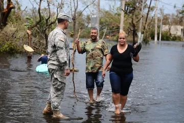 A Puerto Rico National Guard Soldier helps a couple getting away from the flooded areas in Condado San Juan Puerto Rico after the path of Hurricane Maria Photo by Sgt Jose Ahiram Diaz Ramos PRNG PAO CNA