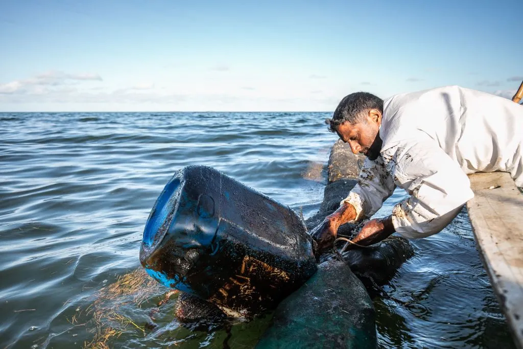 A fisherman places handmade oil barriers into the sea at the Old Grand Port in Mauritius, Aug. 11, 2020, to block leaked oil from the MV Wakashio. ?w=200&h=150