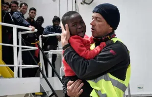 A helper from Doctors Without Borders holds a Nigerian child as a migrant ship arrives at a Sicilian port May 14, 2018.   Louisa Gouliamaki / AFP / Getty Images.