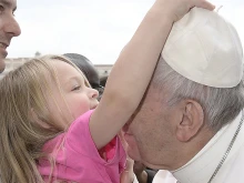 A little girl at the general audience greets Pope Francis and tries to take his zuchetto in St. Peter's Square on March 22, 2017. 