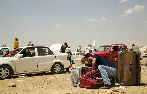 A man leaves his car and packs his bag at the Khazair checkpoint after fleeing from Mosul, Iraq on June 11, 2014. ?w=200&h=150
