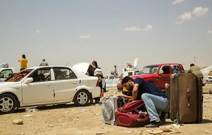 A man leaves his car and packs his bag at the Khazair checkpoint after fleeing from Mosul, Iraq on June 11, 2014.   R. Nuri UNHCR-ACNUR via Flickr (CC BY-NC-SA 2.0)