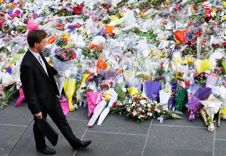 A man places flowers as a mark of respect for the victims of Martin Place siege on December 16, 2014 in Sydney, Australia. ?w=200&h=150