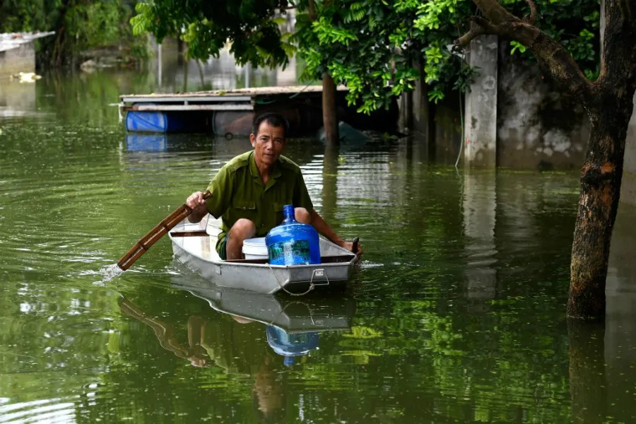A man rows a boat through floodwaters as he brings potable water back to his flooded home in Hanoi's suburban Chuong My district, Aug. 2, 2018. ?w=200&h=150