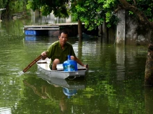 A man rows a boat through floodwaters as he brings potable water back to his flooded home in Hanoi's suburban Chuong My district, Aug. 2, 2018. 