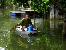 A man rows a boat through floodwaters as he brings potable water back to his flooded home in Hanoi's suburban Chuong My district, Aug. 2, 2018. 