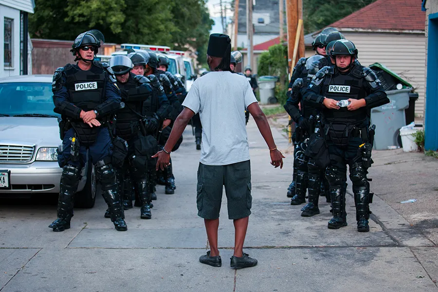 A man talks to police in riot gear as they wait in an alley after a second night of clashes between protestors and police August 15, 2016 in Milwaukee, Wisconsin. ?w=200&h=150