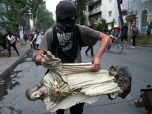 A protester carries a statue of Christ from La Asuncion church to be added to a barricade in Santiago, Chile, Nov 8, 2019. 