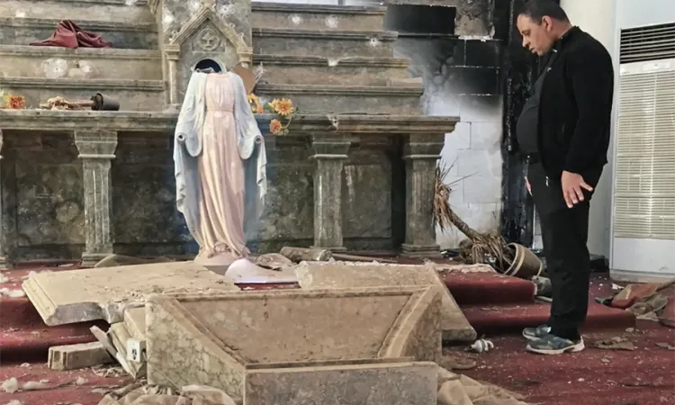A priest surveys the damage caused by ISIS at a Catholic Church in Batnaya Iraq Photo courtesy of Stephen Rasche