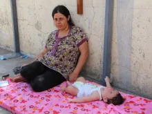 A refugee mother with her child, who is having stomach problems and other issues because of the heat. 