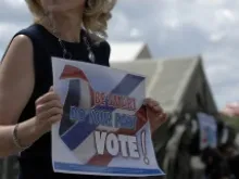 A woman holds a sign encouraging people to vote. 