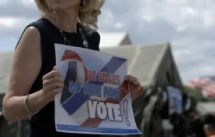 A woman holds a sign encouraging people to vote.   Airman 1st Class Nathan Lipscomb-USAF.