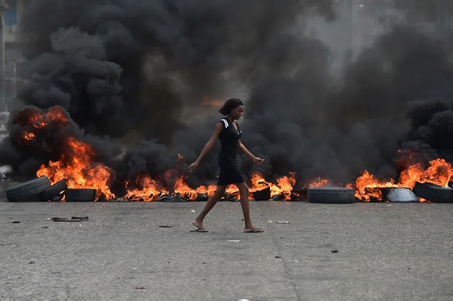 A woman walks past tire barricades set ablaze by demonstrators protesting in Port-au-Prince against Haitian President Jovenel Moise Feb. 10, 2019. ?w=200&h=150
