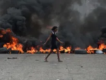 A woman walks past tire barricades set ablaze by demonstrators protesting in Port-au-Prince against Haitian President Jovenel Moise Feb. 10, 2019. 