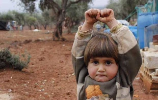 A young Syrian child raises her arms in a gesture of surrender.   Osman Sagirli.