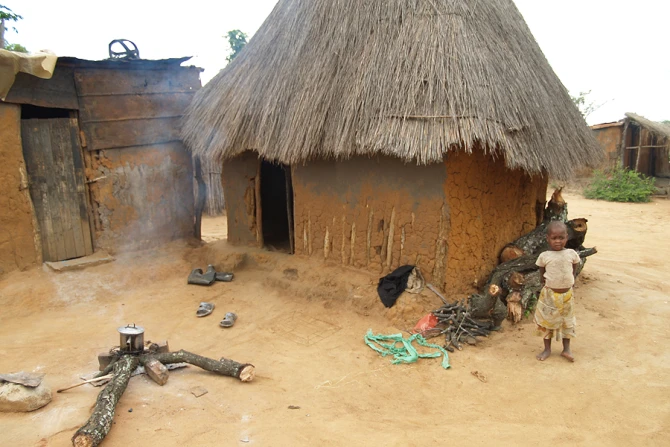 A young boy stands in front of a smiple mud hut in a village in the Diocese of Chinhoyi in Zimbabwe Credit Jesuitenmission CNA 12 17 14