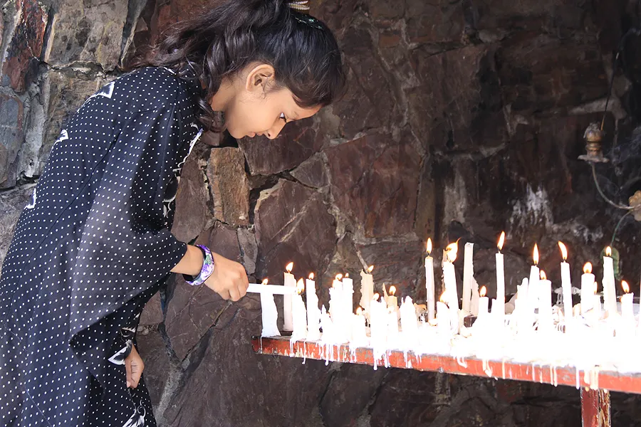 A young girl lights a candle at a Marian Grotto in Pakistan.?w=200&h=150