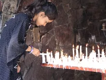 A young girl lights a candle at a Marian grotto in Pakistan. 