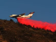 An air tanker drops fire retardant over power lines while helping to fight the Hillside Fire in San Bernardino, California, Oct. 31, 2019. 