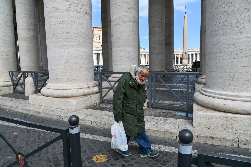 An elderly homeless man walks along the colonnade of St. Peter's Square, March 15, 2020, days after their closure to tourists. ?w=200&h=150