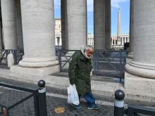 An elderly homeless man walks along the colonnade of St. Peter's Square, March 15, 2020, days after their closure to tourists. 