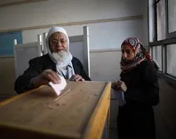 An election official (R) watches as an elderly man votes at a polling station in Old Cairo. ?w=200&h=150