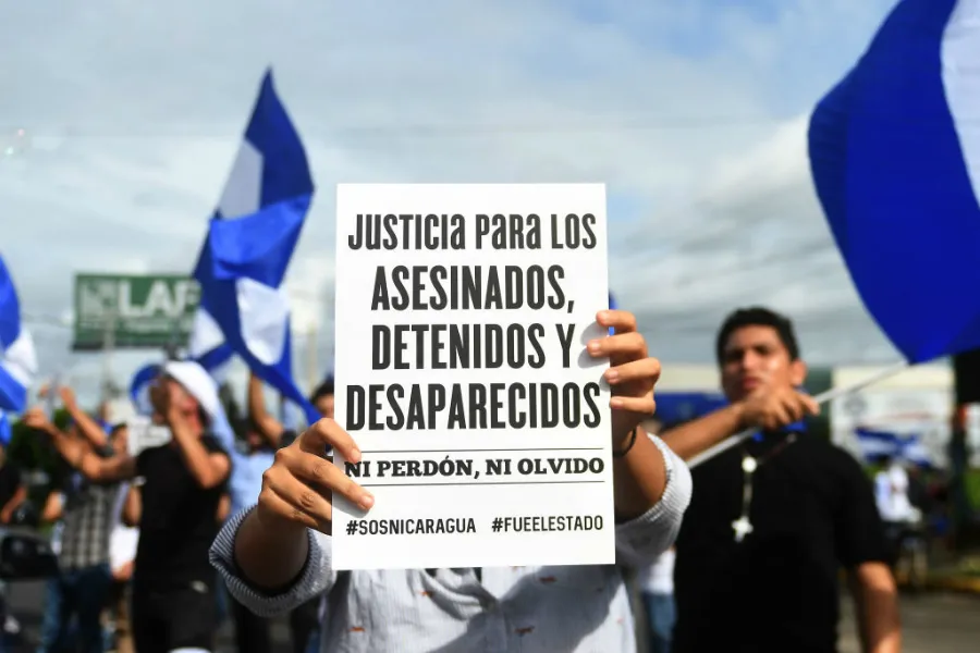 An anti-government demonstrator holds a sign in Managua, June 17, 2018, after a family died when their house was burnt on Saturday. ?w=200&h=150