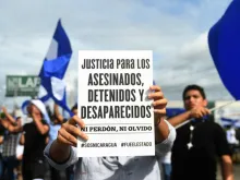 An anti-government demonstrator holds a sign in Managua, June 17, 2018, after a family died when their house was burnt on Saturday. 