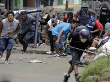 Anti-government demonstrators take cover behind a barricade, during clashes with riot police and members of the Sandinista youth, in Masaya, June 19, 2018. 