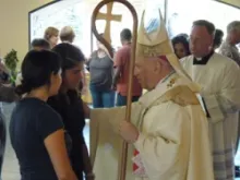 Archbishop Samuel J Aquila comforts a parishioner at Queen of Peace Catholic Church on the evening of July 20, 2012.