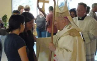 Archbishop Samuel J Aquila comforts a parishioner at Queen of Peace Catholic Church on the evening of July 20, 2012. 