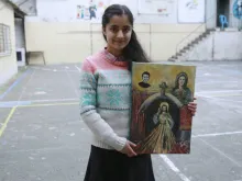 Syrian refugee Sarah, 14, displays a painting she made for Pope Francis. 