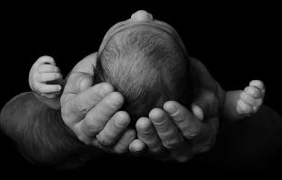 Baby in parent's arms. geliatida via Shutterstock.