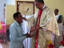 Bishop George Pallipparambil presents the New Testament in Wancho to a parishioner at the Chrism Mass, March 27, 2015. 