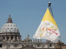 The flag of Vatican City with St. Peter's Basilica in the background. 